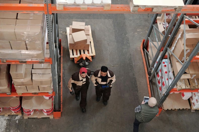 Top view of warehouse team discussing pallet shipments and inventory flow as part of order processing.