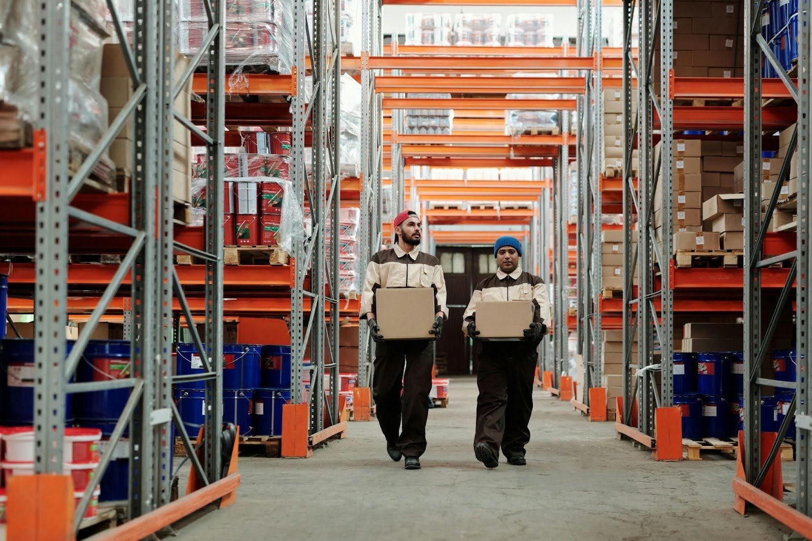 Warehouse employees carrying boxes through storage aisles, highlighting manual steps in B2B order processing.